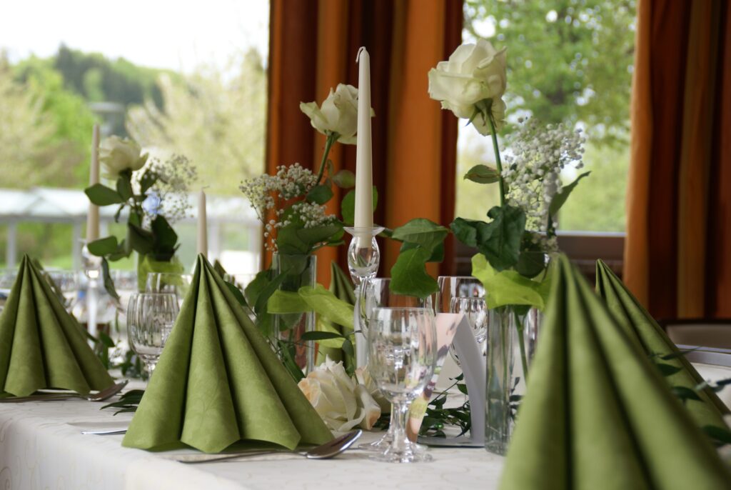 Tischdekoration Mezzos, Tisch mit grünen Servietten und weißen Kerzen sowie Rosen